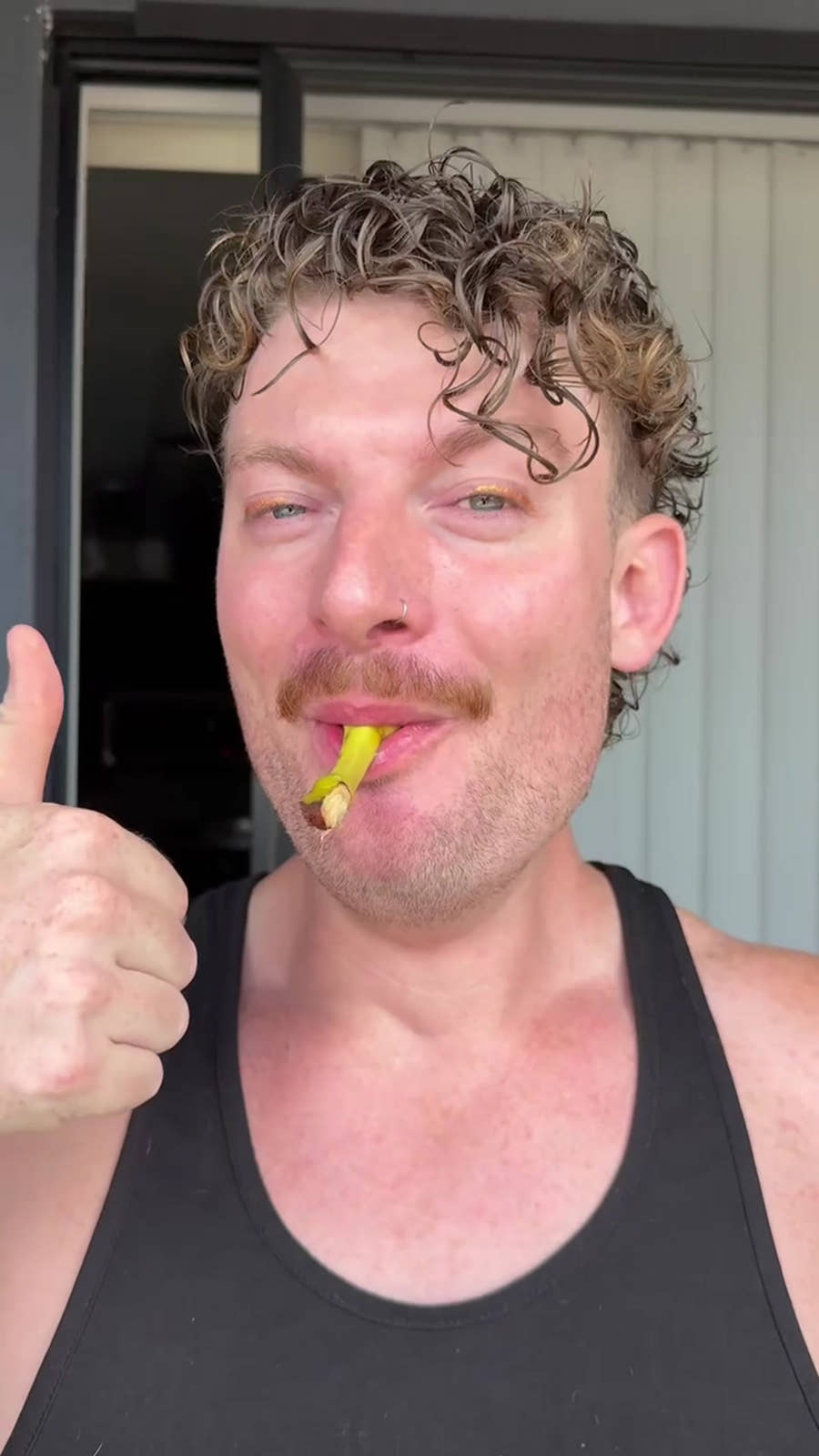 Alex gives a thumbs up with a banana in his mouth after using GoBlo